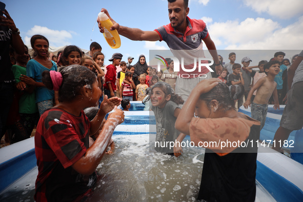 Palestinian children are playing with water and soap to cool themselves down during a heatwave at a temporary camp for the internally displa...