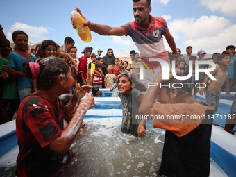 Palestinian children are playing with water and soap to cool themselves down during a heatwave at a temporary camp for the internally displa...