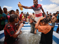 Palestinian children are playing with water and soap to cool themselves down during a heatwave at a temporary camp for the internally displa...