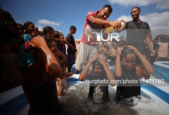 Palestinian children are playing with water and soap to cool themselves down during a heatwave at a temporary camp for the internally displa...