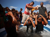 Palestinian children are playing with water and soap to cool themselves down during a heatwave at a temporary camp for the internally displa...