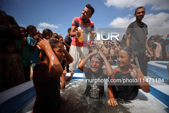 Palestinian children are playing with water and soap to cool themselves down during a heatwave at a temporary camp for the internally displa...