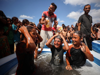 Palestinian children are playing with water and soap to cool themselves down during a heatwave at a temporary camp for the internally displa...