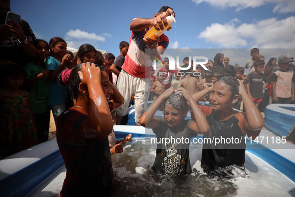 Palestinian children are playing with water and soap to cool themselves down during a heatwave at a temporary camp for the internally displa...