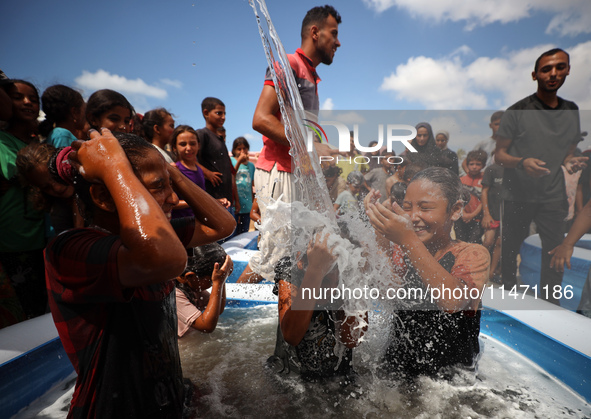 Palestinian children are playing with water and soap to cool themselves down during a heatwave at a temporary camp for the internally displa...