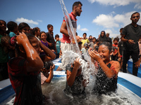 Palestinian children are playing with water and soap to cool themselves down during a heatwave at a temporary camp for the internally displa...