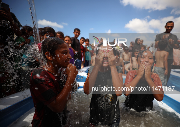 Palestinian children are playing with water and soap to cool themselves down during a heatwave at a temporary camp for the internally displa...