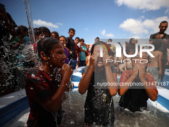 Palestinian children are playing with water and soap to cool themselves down during a heatwave at a temporary camp for the internally displa...