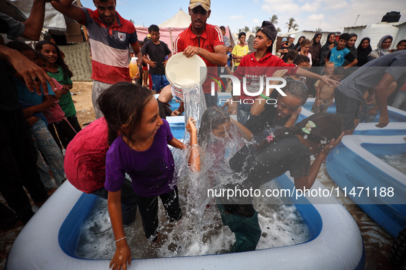 Palestinian children are playing with water and soap to cool themselves down during a heatwave at a temporary camp for the internally displa...