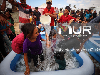 Palestinian children are playing with water and soap to cool themselves down during a heatwave at a temporary camp for the internally displa...