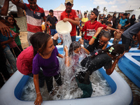 Palestinian children are playing with water and soap to cool themselves down during a heatwave at a temporary camp for the internally displa...