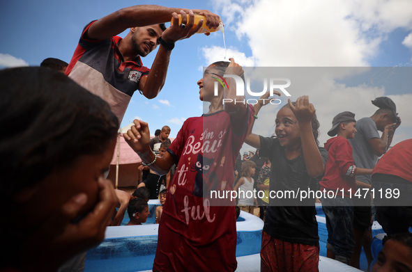 Palestinian children are playing with water and soap to cool themselves down during a heatwave at a temporary camp for the internally displa...