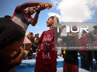 Palestinian children are playing with water and soap to cool themselves down during a heatwave at a temporary camp for the internally displa...