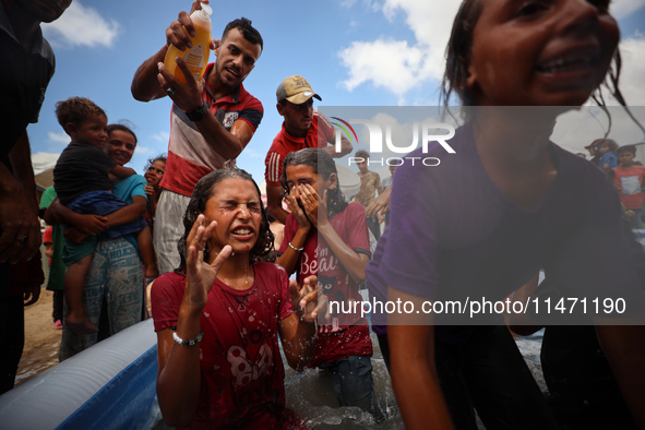 Palestinian children are playing with water and soap to cool themselves down during a heatwave at a temporary camp for the internally displa...