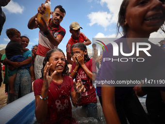 Palestinian children are playing with water and soap to cool themselves down during a heatwave at a temporary camp for the internally displa...