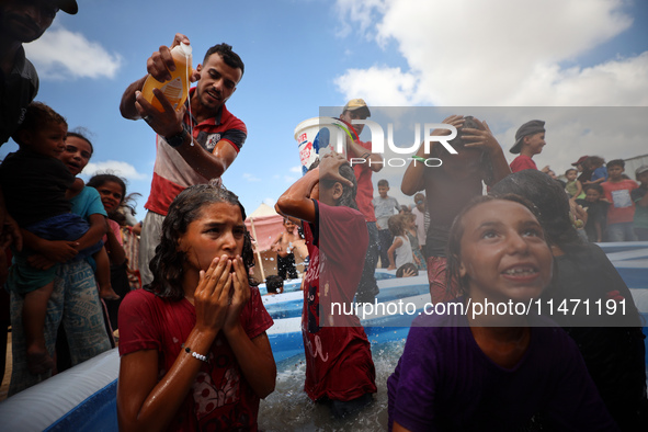 Palestinian children are playing with water and soap to cool themselves down during a heatwave at a temporary camp for the internally displa...