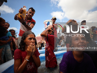 Palestinian children are playing with water and soap to cool themselves down during a heatwave at a temporary camp for the internally displa...