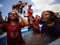 Palestinian children are playing with water and soap to cool themselves down during a heatwave at a temporary camp for the internally displa...