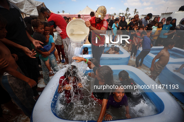 Palestinian children are playing with water and soap to cool themselves down during a heatwave at a temporary camp for the internally displa...