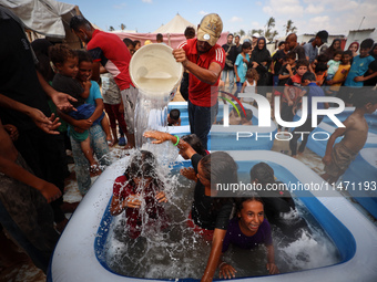 Palestinian children are playing with water and soap to cool themselves down during a heatwave at a temporary camp for the internally displa...