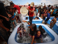 Palestinian children are playing with water and soap to cool themselves down during a heatwave at a temporary camp for the internally displa...