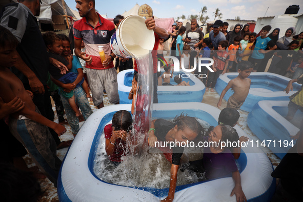 Palestinian children are playing with water and soap to cool themselves down during a heatwave at a temporary camp for the internally displa...