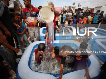 Palestinian children are playing with water and soap to cool themselves down during a heatwave at a temporary camp for the internally displa...