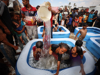 Palestinian children are playing with water and soap to cool themselves down during a heatwave at a temporary camp for the internally displa...