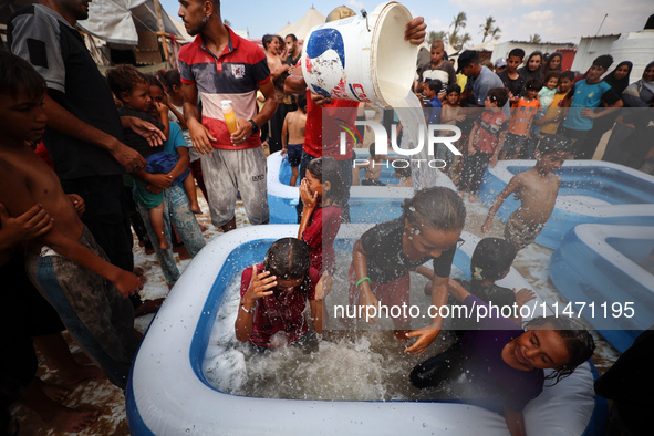 Palestinian children are playing with water and soap to cool themselves down during a heatwave at a temporary camp for the internally displa...