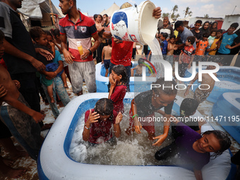 Palestinian children are playing with water and soap to cool themselves down during a heatwave at a temporary camp for the internally displa...