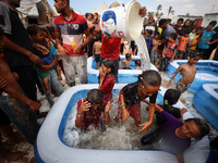 Palestinian children are playing with water and soap to cool themselves down during a heatwave at a temporary camp for the internally displa...