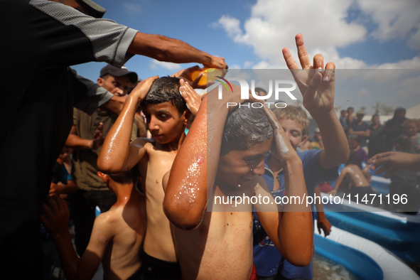 Palestinian children are playing with water and soap to cool themselves down during a heatwave at a temporary camp for the internally displa...