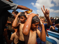 Palestinian children are playing with water and soap to cool themselves down during a heatwave at a temporary camp for the internally displa...