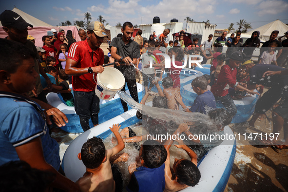 Palestinian children are playing with water and soap to cool themselves down during a heatwave at a temporary camp for the internally displa...