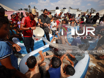 Palestinian children are playing with water and soap to cool themselves down during a heatwave at a temporary camp for the internally displa...