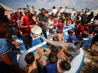 Palestinian children are playing with water and soap to cool themselves down during a heatwave at a temporary camp for the internally displa...