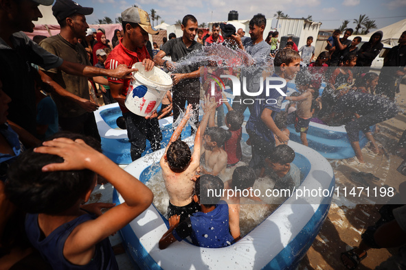 Palestinian children are playing with water and soap to cool themselves down during a heatwave at a temporary camp for the internally displa...