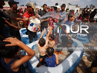 Palestinian children are playing with water and soap to cool themselves down during a heatwave at a temporary camp for the internally displa...