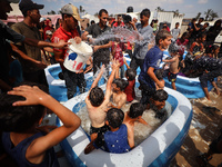 Palestinian children are playing with water and soap to cool themselves down during a heatwave at a temporary camp for the internally displa...