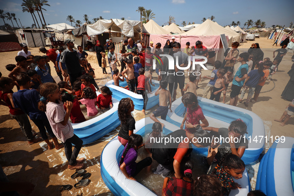 Palestinian children are playing with water and soap to cool themselves down during a heatwave at a temporary camp for the internally displa...