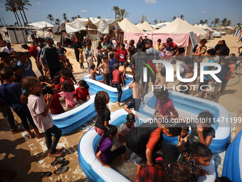 Palestinian children are playing with water and soap to cool themselves down during a heatwave at a temporary camp for the internally displa...