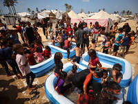 Palestinian children are playing with water and soap to cool themselves down during a heatwave at a temporary camp for the internally displa...