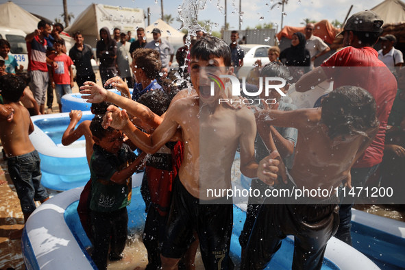 Palestinian children are playing with water and soap to cool themselves down during a heatwave at a temporary camp for the internally displa...