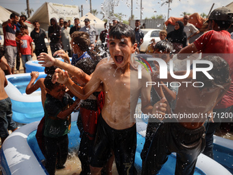 Palestinian children are playing with water and soap to cool themselves down during a heatwave at a temporary camp for the internally displa...