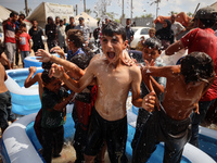 Palestinian children are playing with water and soap to cool themselves down during a heatwave at a temporary camp for the internally displa...