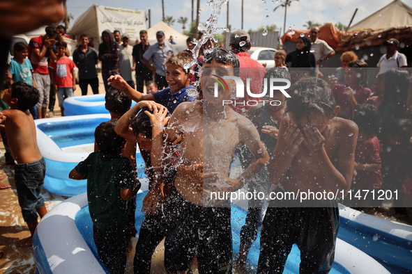 Palestinian children are playing with water and soap to cool themselves down during a heatwave at a temporary camp for the internally displa...