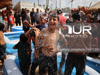 Palestinian children are playing with water and soap to cool themselves down during a heatwave at a temporary camp for the internally displa...