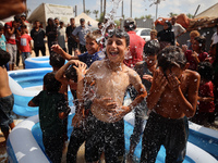 Palestinian children are playing with water and soap to cool themselves down during a heatwave at a temporary camp for the internally displa...