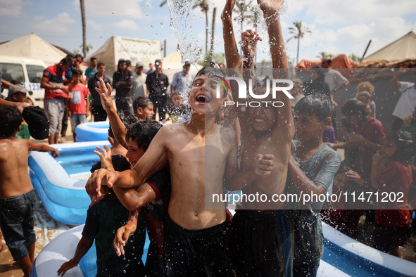 Palestinian children are playing with water and soap to cool themselves down during a heatwave at a temporary camp for the internally displa...