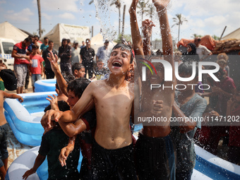 Palestinian children are playing with water and soap to cool themselves down during a heatwave at a temporary camp for the internally displa...